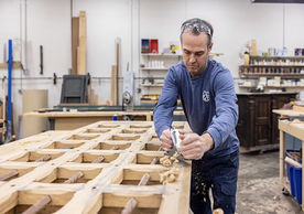 Woodworker planing a large wooden door in a workshop, photo by Robert DeSanto